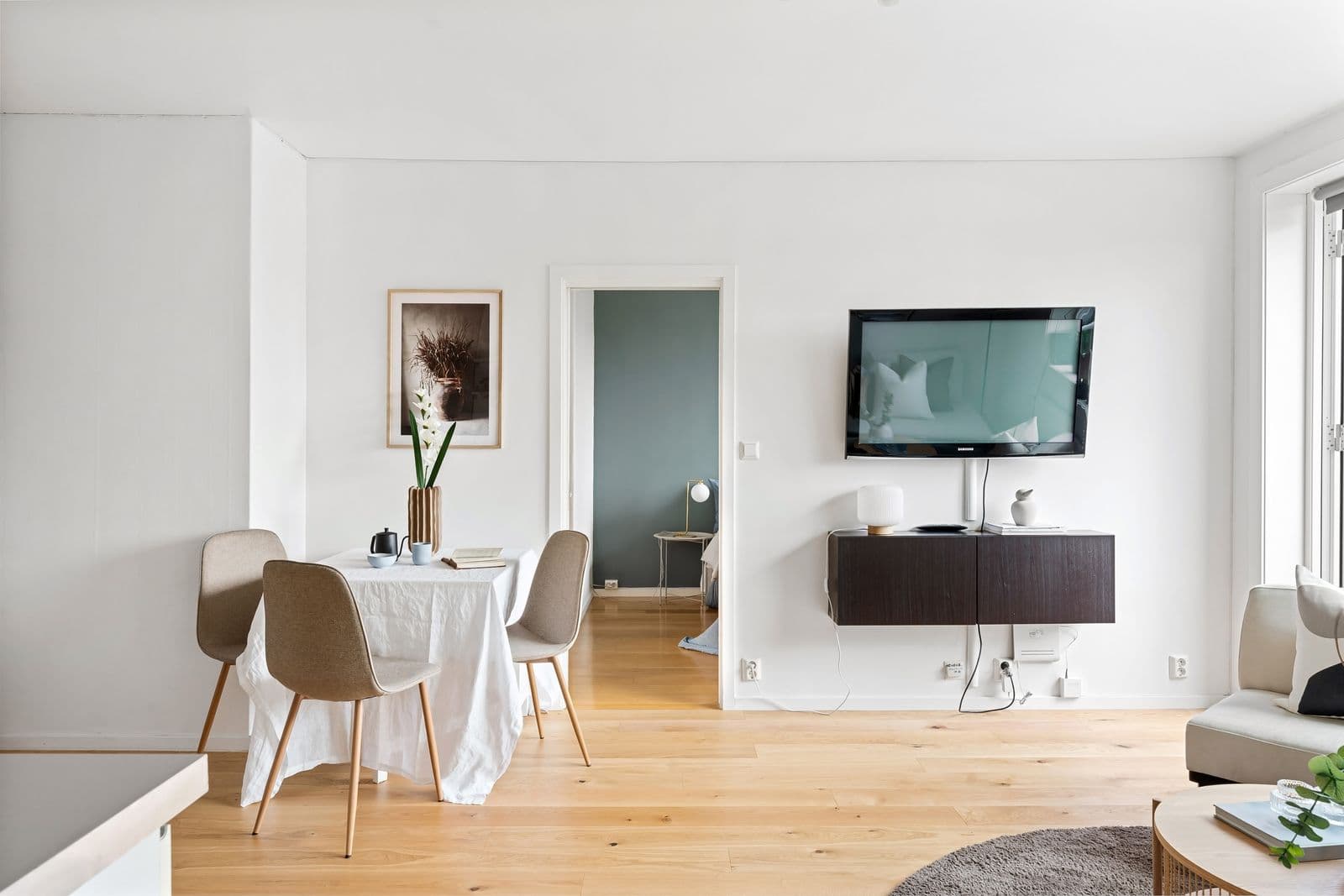 Samsung TV mounted flush on a bright white wall above a floating console